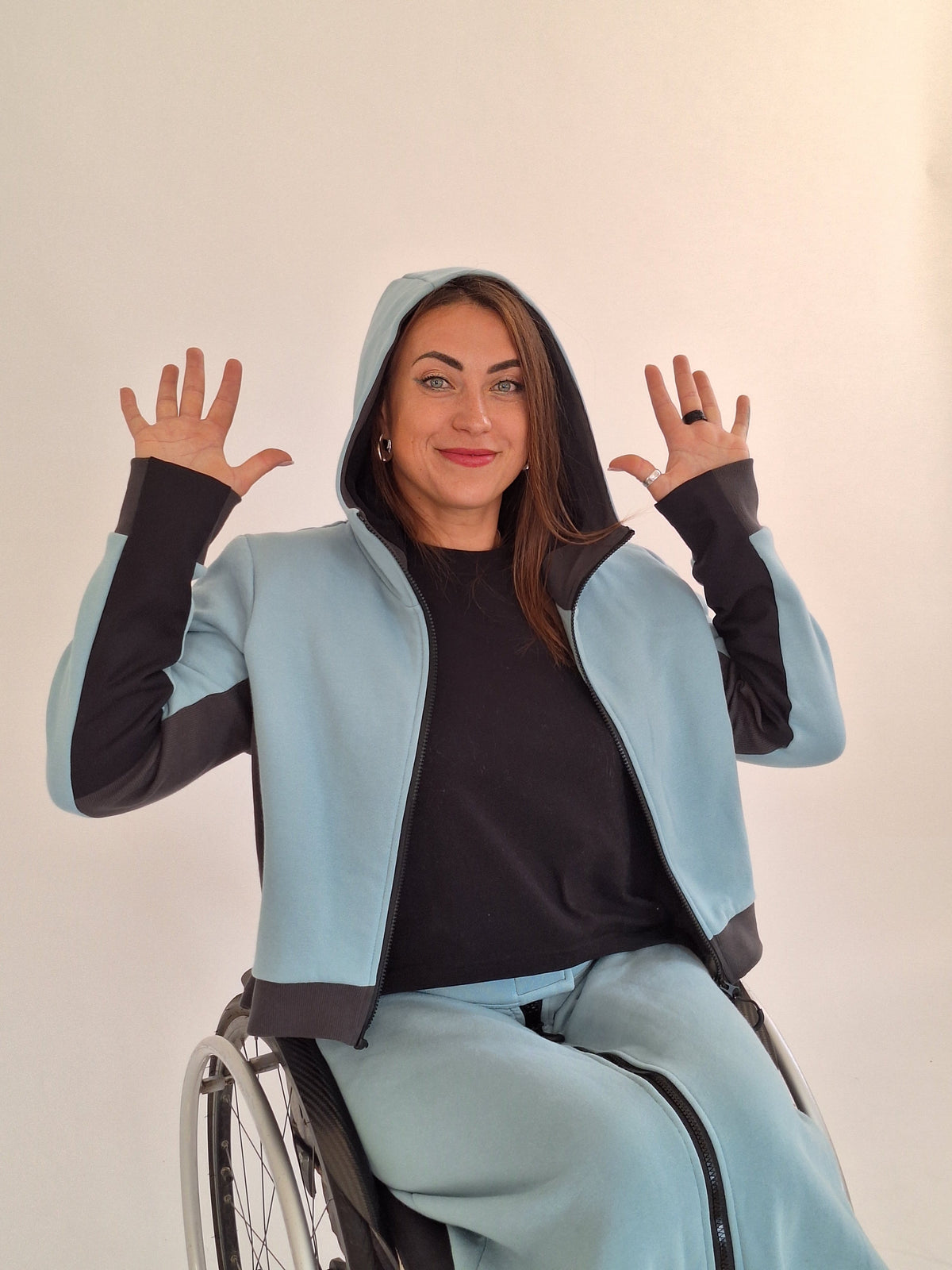 A smiling woman in a wheelchair showcasing adaptive clothing made by Vilber's