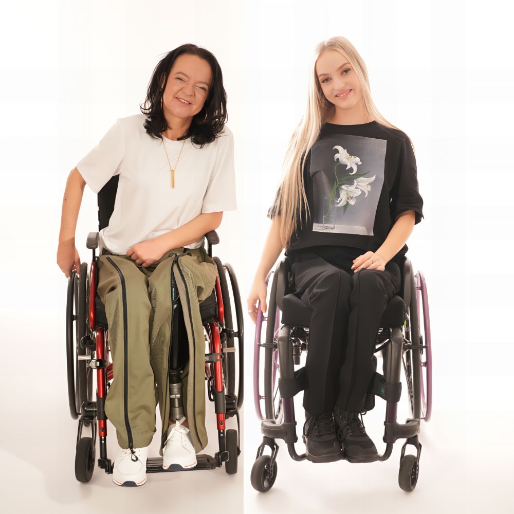 Two smiling women in wheelchairs showcasing adaptive clothing made by Vilber's
